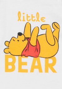 Orso cartoon giallo sdraiato sulla schiena, che indossa una maglietta rossa, con il testo "little BEAR" in arancione sotto su uno sfondo bianco.