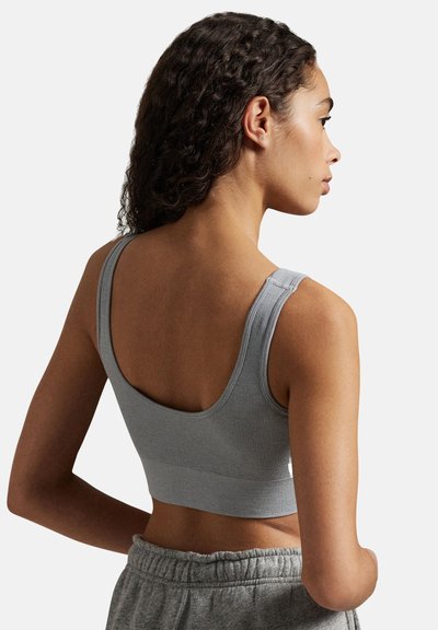 Grå ribbad sport-bh med breda band, rundad rygg och figurnära design, kombinerad med lösa grå byxor. Mjuk tygstruktur.
