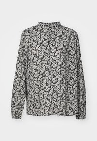 Blouse noire à manches longues avec motif floral blanc, col haut et petite ouverture en forme de clé à l'avant.