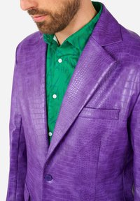 Purple leather blazer with crocodile texture, featuring a chest pocket and single button closure, worn over a green patterned shirt.
