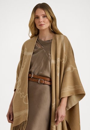 Beige uld tørklæde med tekstureret detaljering draperet over en satin brun kjole, suppleret med et brun læderbælte med sølvbeslag.