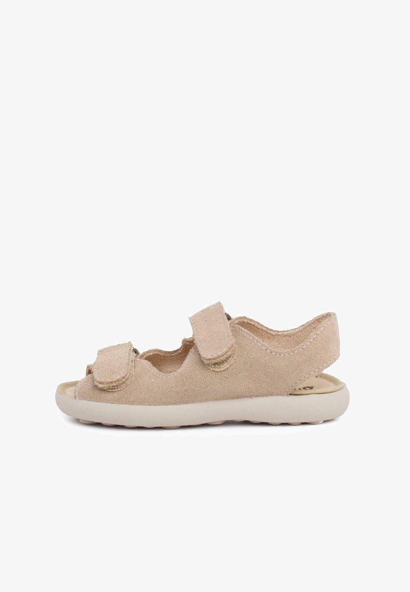 Beige suede sandal with two adjustable hook-and-loop straps, open toe, curved back, and a lightweight cream rubber sole.