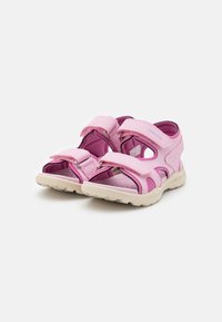 Suunnittelu vaaleanpunaisista sandaaleista, joissa on kaksi tarranauhaa, hengittävä materiaali ja teksturoitu beige pohja. Sisältää leikkausdetaljeja ja logomerkintöjä.