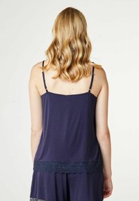 Kongelig blå cami lavet af blødt stof med justerbare stropper, der har en blonde trim langs kanten og en standard pasform.