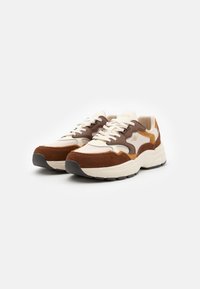 Sneakers with a cream mesh upper, brown suede accents, and beige leather details. Thick white sole with black rubber tread and laces.