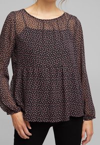 Blusa nera con stampa floreale bianca e rosa. Maniche lunghe trasparenti, scollatura arricciata e vita a peplo. Tessuto morbido e leggero.