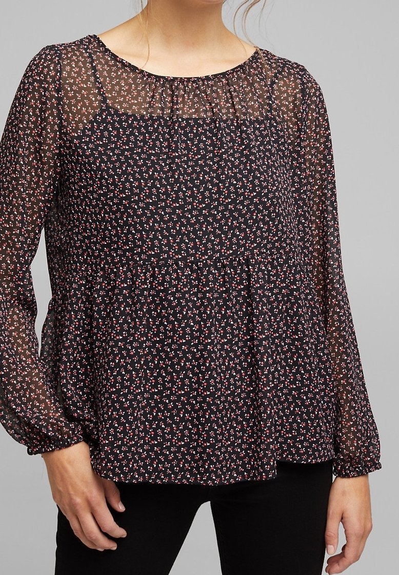 Blusa nera con stampa floreale bianca e rosa. Maniche lunghe trasparenti, scollatura arricciata e vita a peplo. Tessuto morbido e leggero.
