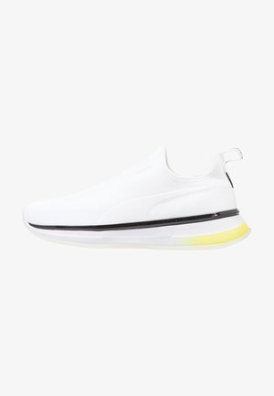Baskets de sport blanches avec un dessus en maille texturée, design sans lacets, bandeau noir, et une semelle jaune. Pas de lacets visibles.