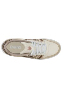 Zapatilla deportiva blanca y beige con rayas marrones y acentos de estampado de leopardo. Presenta un diseño de cordones y una plantilla acolchada.