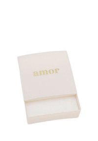 Piccola scatola quadrata bianca per gioielli con testo dorato "amor" sul coperchio, parzialmente aperta che mostra l'interno vuoto.