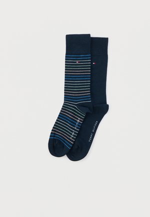 Pari tummansinisiä kajosisäkaluja, toinen yksivärinen ja toinen monivärisillä vaakaraitojen kanssa, molemmissa pienet Tommy Hilfiger -logot.