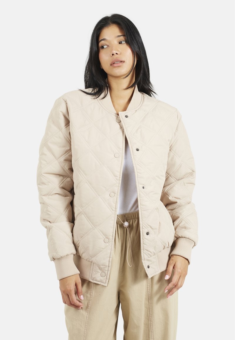 Veste bomber matelassée beige avec un col côtelé, fermeture à boutons-pression et poches latérales. Texture douce avec un motif en losanges.