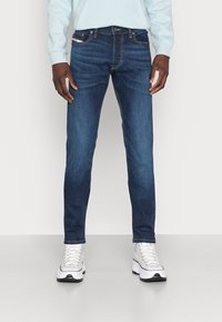 Mörkblå jeans i denim med en smal passform, som har fem fickor, orangea sömnadsdetaljer och dragkedja vid gylfen.