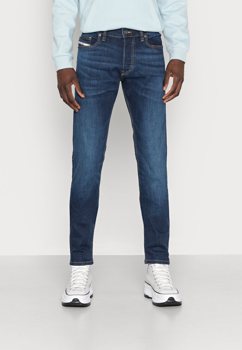 Mörkblå jeans i denim med en smal passform, som har fem fickor, orangea sömnadsdetaljer och dragkedja vid gylfen.