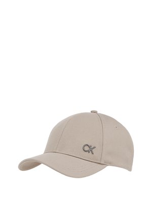 Cappellino da baseball beige in tessuto strutturato con visiera curva e fori di ventilazione cuciti, caratterizzato da un piccolo logo metallico "CK" sul davanti.