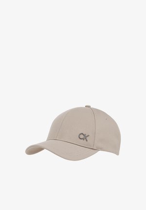 Cappellino da baseball beige in tessuto strutturato con visiera curva e fori di ventilazione cuciti, caratterizzato da un piccolo logo metallico "CK" sul davanti.