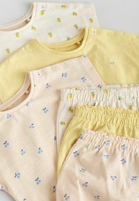 Set van kinderkleding met lichte stoffen. Twee gele tops, waarvan één met kleine ananasprints, plus onderstukken met kersenontwerp.
