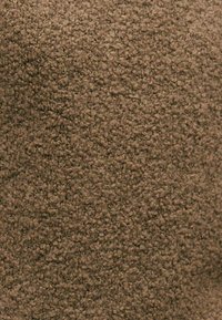Tejido marrón texturizado con una superficie suave y peluda y bucles apretados, adecuado para tapicería o alfombra.
