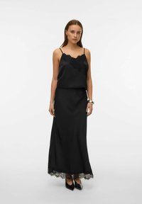 Zwarte satijnen jurk met kantafwerking langs de zoom. Verstelbare spaghetti bandjes, losvallende pasvorm aan de bovenkant, ontwerp tot op de grond, en een gladde textuur.
