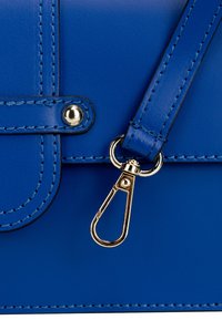 Modrá kožená taška s hladkou texturou, s pozlaceným kovovým zapínáním a švy, s odnímatelným popruhem.