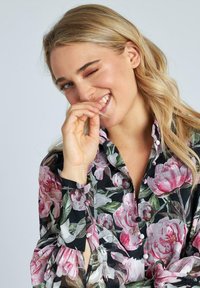 Blusa floreale con sfondo nero e grandi motivi di peonie rosa, maniche lunghe con chiusura a bottoni e design colletto classico.
