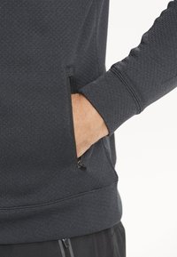 Tummanharmaa collegepaita, jossa on tekstuuripinta, varustettuna vetoketjullisella sivutaskulla ja ribbauslahkeilla. Rentoa mallia, jossa on suora siluetti.