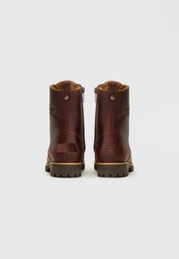 Botas de tobillo de cuero marrón con un acabado texturizado, cremalleras laterales y suelas de goma. Presenta costuras y un parche con la marca en el talón.