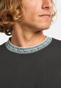 Dark gray pullover with a textured finish. Features a patterned collar in white, gray, and light teal. Close-up of neck area and shoulder.
