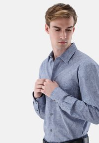 Hellblaues, langärmliges Hemd mit Knopfleiste, verziert mit einem filigranen Ton-in-Ton-Muster, Kragen und geknöpften Manschetten; der Stoff wirkt glatt und strukturiert.