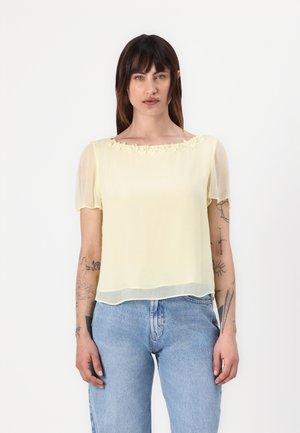 Geel chiffon blouse met korte puffmouwen en bloemaccenten bij de halslijn, gecombineerd met blauwe jeans. Glad textuur, ontspannen pasvorm.