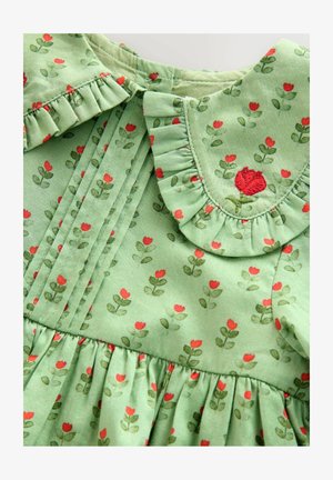 Zöld ruha virágmintával, piros virágokkal és zöld levelekkel. Ráncolt gallér hímzett rózsa díszítéssel és ráncolt derékkal.
