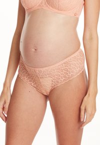 Culotte de maternité en dentelle pêche clair, ornées de motifs de feuilles délicats, avec des bords festonnés et une texture douce et extensible conçue pour le confort.