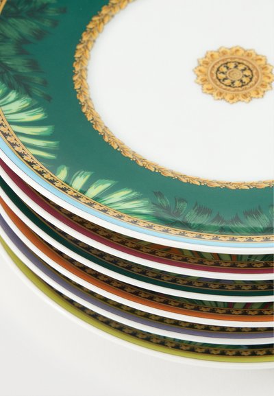 Pile d'assiettes en céramique ornées de bordures vertes, orange et violettes, motifs décoratifs dorés et dessins feuillus sur fond blanc.