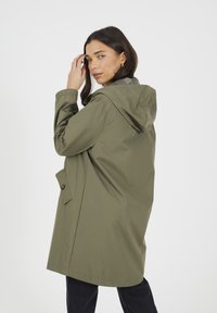 Oliwkowa wodoodporna kurtka z kapturem o luźnym kroju, wyposażona w boczne kieszenie, zapięcie na guziki oraz elastyczne mankiety do regulowania dopasowania.