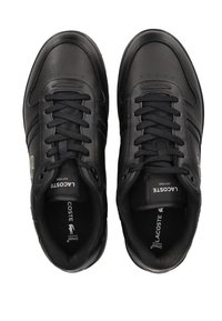 Black leather sneakers with round toe, flat laces, and textured accents. Features a green logo on the side and brand label on the tongue.