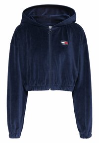 Navyblauwe cropped zip-up hoodie gemaakt van zacht fluweel, met een trekkoordcapuchon en een klein logo-opdruk op de borst.