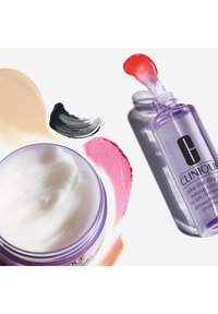 Baume nettoyant Clinique dans un pot violet, avec une texture lisse et blanche ; accompagné d'un démaquillant liquide dans une bouteille violette transparente, échantillons rouge et rose.