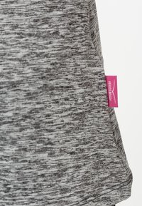 Tejido gris jaspeado con una textura suave. Presenta una etiqueta de marca rosa en el lado cerca del dobladillo. Diseño simple y casual.