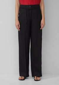 Zwarte linnen wijde broek met een knoopsluiting en een trekkoord in de taille, voorzien van een soepele textuur en een relaxte pasvorm.