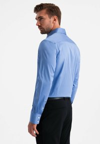 Lichtblauw overhemd met lange mouwen en een gestructureerde kraag, slim fit, met witte knopen op de manchetten, gecombineerd met zwarte broek.