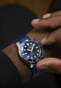 Zegarek Timex Deepwater z niebieskim kauczukowym paskiem i stalową obudow�ą. Tarcza wyróżnia się wzorem fal, luminescencyjnymi znacznikami oraz jednostronnie obracanym pierścieniem.