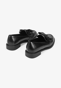 Black leather loafers with a low profile, featuring a decorative bow on the top. Smooth texture and a durable rubber sole.