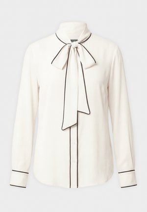 Kreminė palaidinė ilgomis rankovėmis su juoda apdaila, priekyje sagomis užsegama ir prie kaklo surišama kaspinėlis.