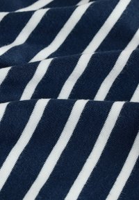 Tessuto a righe blu navy e bianco, con strisce larghe alternate in morbido cotone dalla consistenza liscia, su uno sfondo piegato.