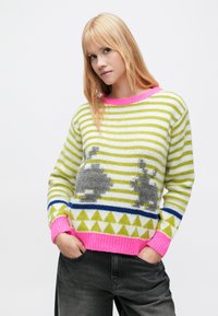 Pletený sveter s pruhmi v zelenej a bielej farbe, zdobený šedými vzormi zajacov, s ružovým rebrovaným golierom a lemom a trojuholníkovým vzorom v modrej a zelenej farbe.