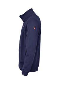 Granatowa bluza z zamkiem błyskawicznym, z wysokim kołnierzem, prążkowanymi mankietami i naszywką na ramieniu. Wykonana z teksturowanej tkaniny bawełnianej.