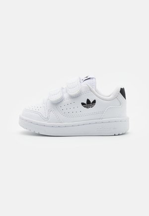 Zapatilla blanca de cuero con tiras de Velcro, puntera perforada, logo negro, entresuela blanca y suela texturizada para tracción.