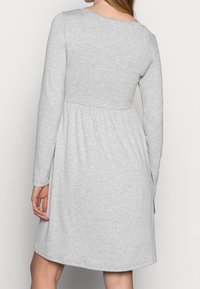 Grå långärmad klänning i mjukt tyg, med en figursydd bodice och utsvängd kjol, rund halsringning och elastisk midja.