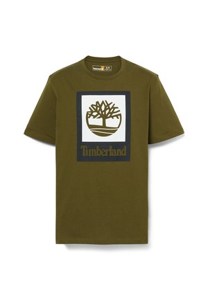 Oliwkowa koszulka z krótkim rękawem z białym kwadratem w czarnej ramce, z stylizowanym logo drzewa i napisem „Timberland” poniżej.