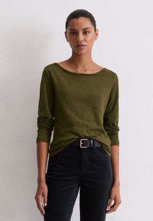 Olive green long-sleeve top with a wide neckline, soft texture, and rolled sleeves, paired with black high-waisted pants and a black belt.